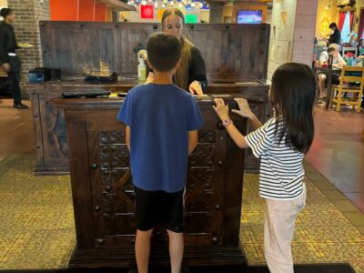 2 kids standing in front of a waiting staff at a restaurant